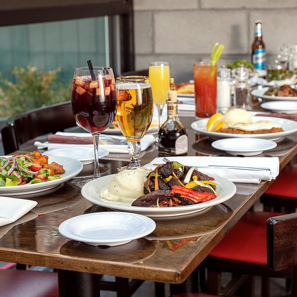 A table laden with Argentinian dishes, including steak, mashed potatoes, salad, and various drinks.