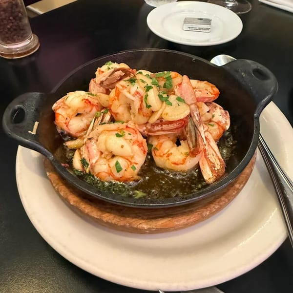 Sizzling Argentinian garlic shrimp (gambas al ajillo) in a black cast iron skillet, garnished with parsley.
