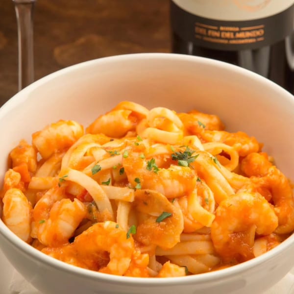 Close-up of a white bowl filled with shrimp and calamari pasta in a rich red sauce.